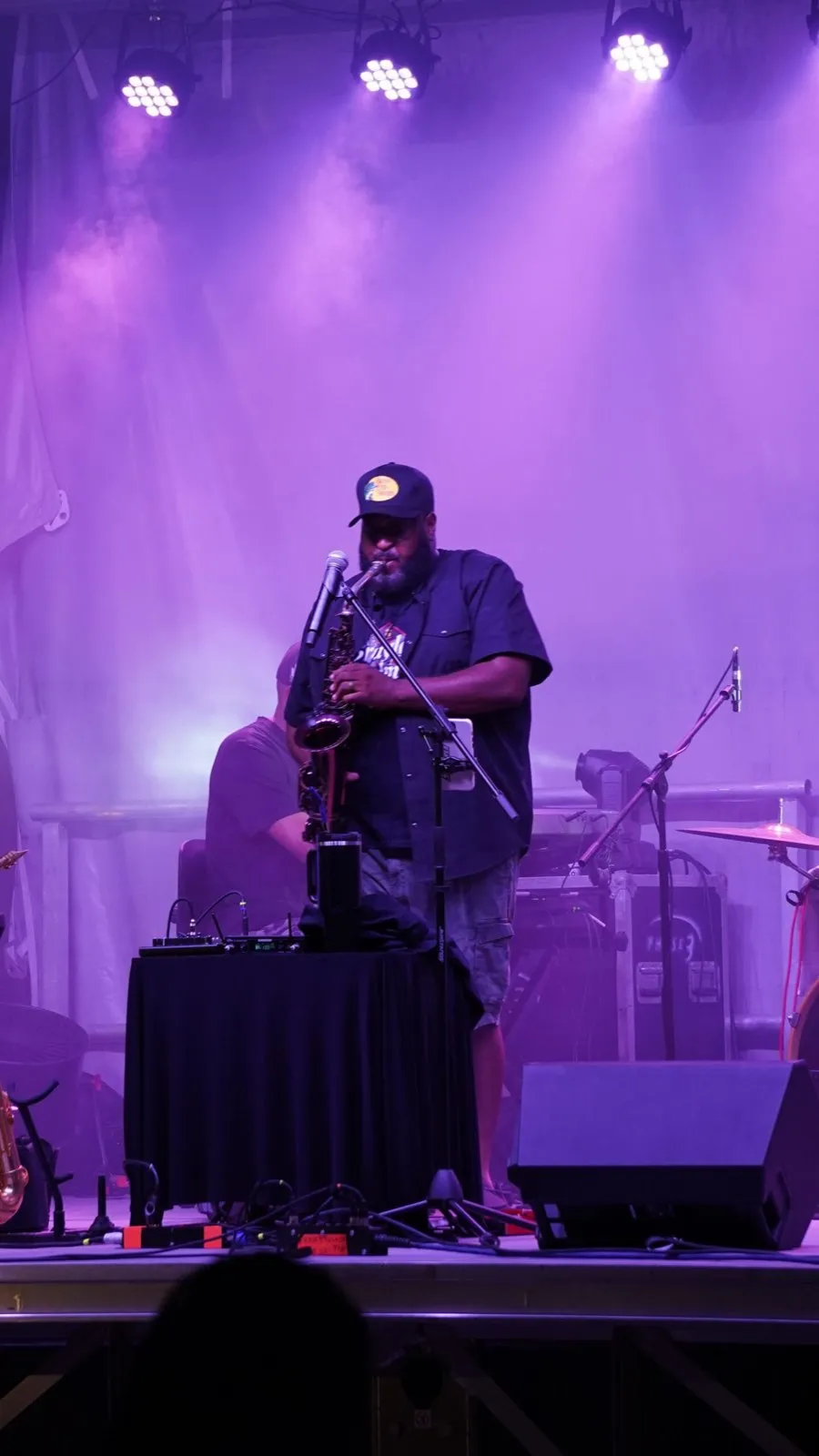 Saxophonist performing under purple stage lighting at a live event produced by Phase 3 Live