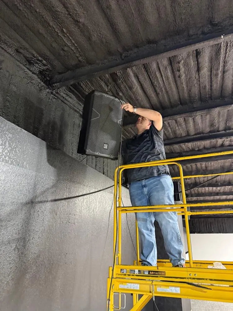 Phase 3 Live technician mounting a loudspeaker from a scaffold during a venue audio installation