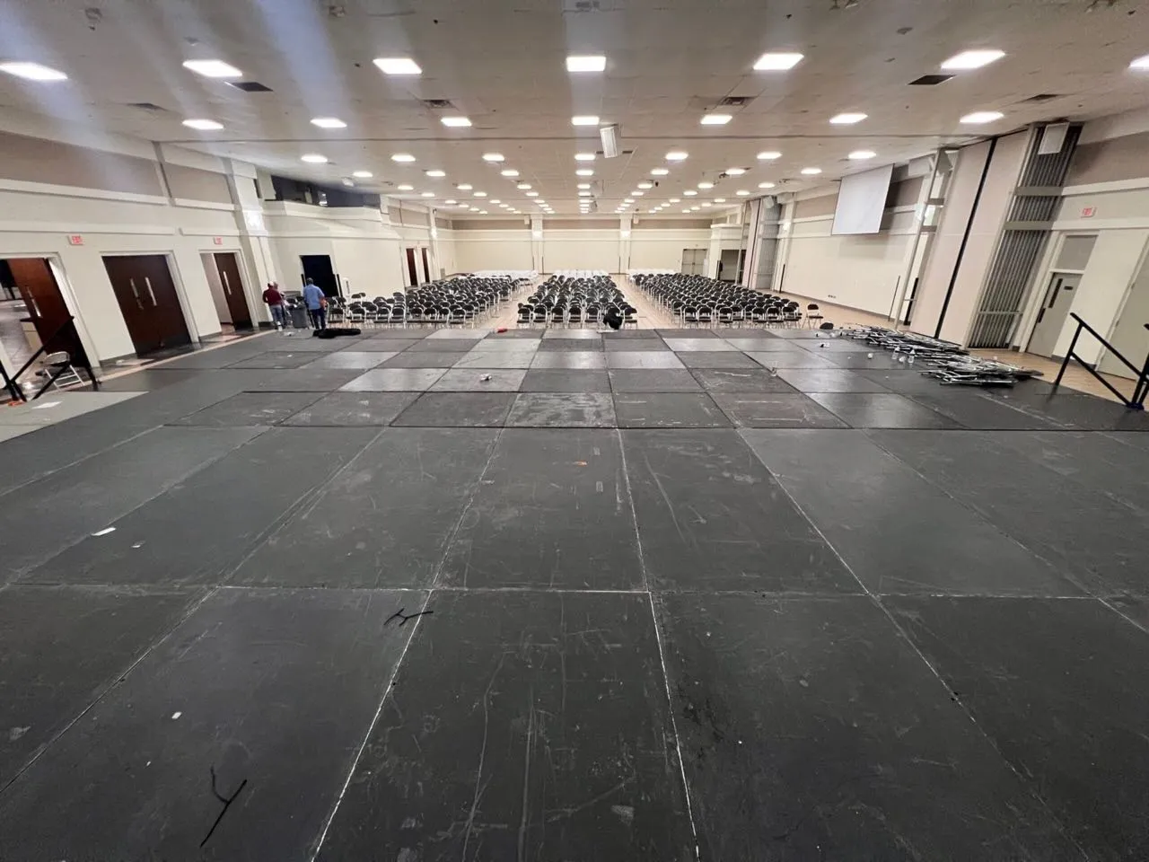 Modular stage decking installed by Phase 3 Live across the floor of a convention hall set with rows of chairs