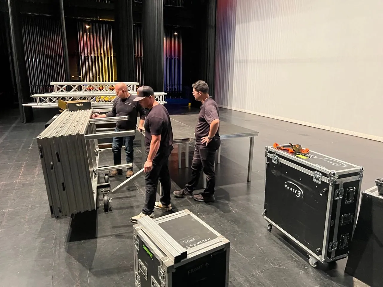 Phase 3 Live technicians setting up portable stage decking inside a theater