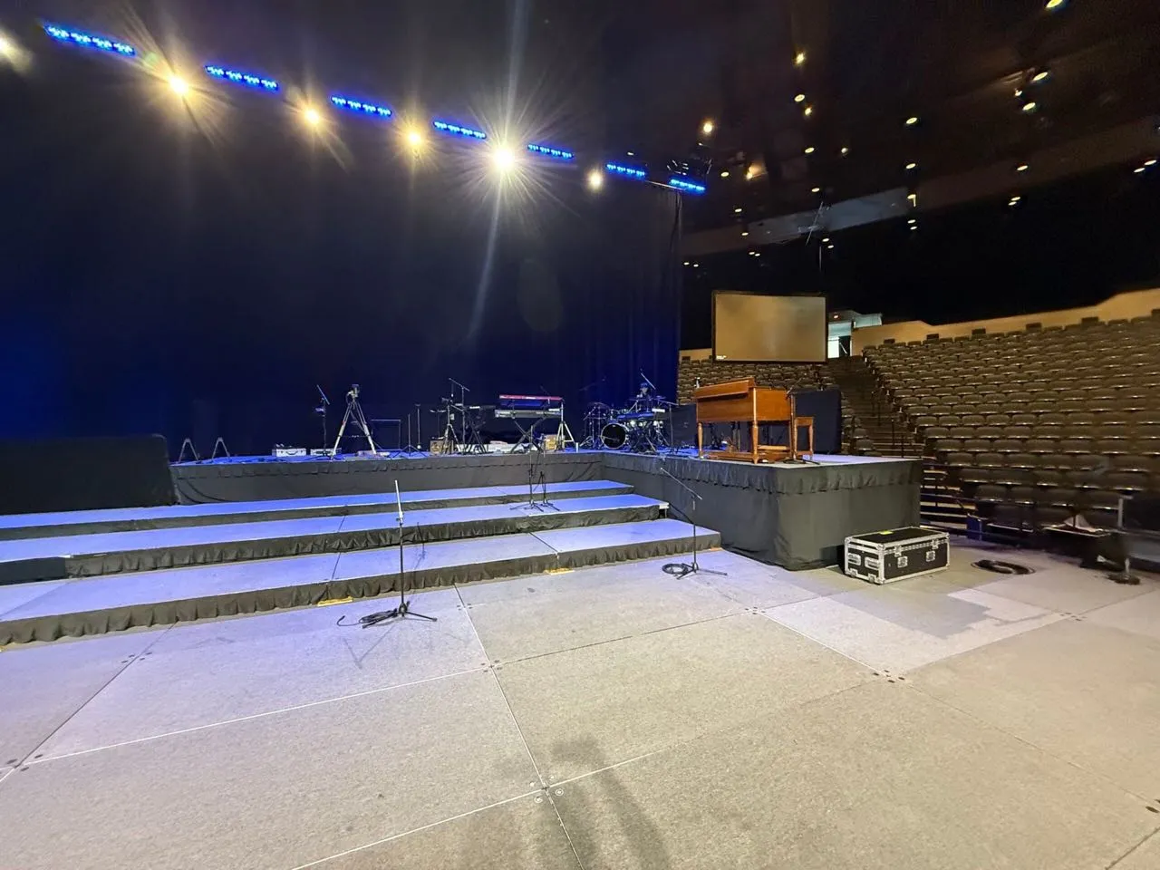 Custom stage decking and band setup built by Phase 3 Live in an auditorium before doors