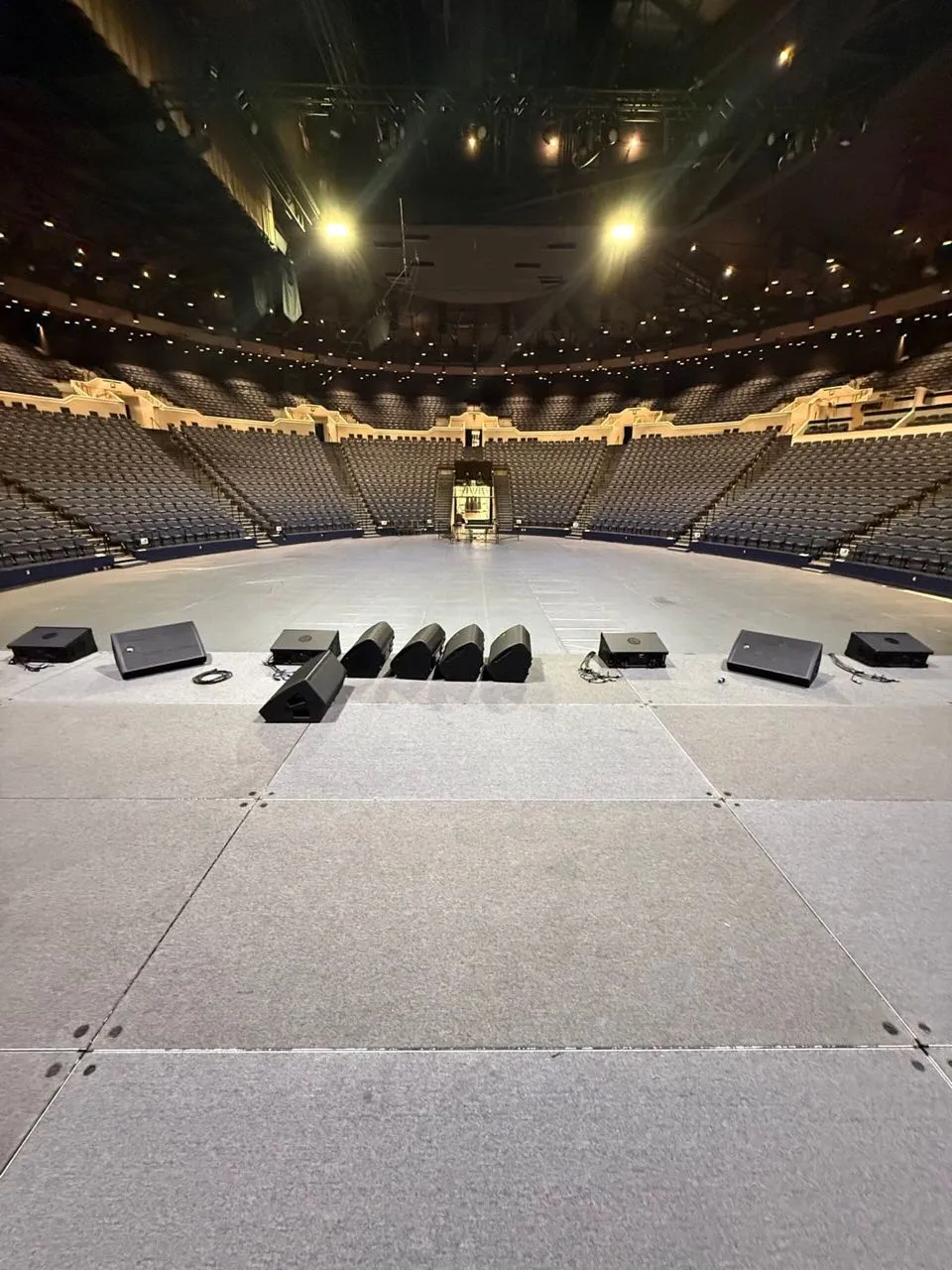 Stage monitors lined across an arena stage during a Phase 3 Live setup