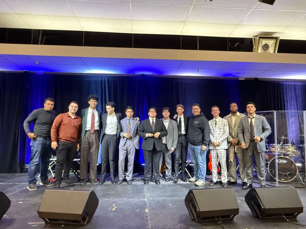 Performers in suits lined up on stage after an event produced by Phase 3 Live