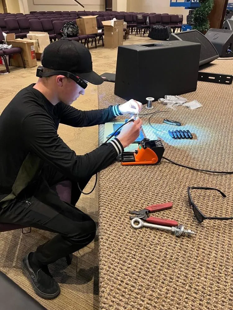 Phase 3 Live technician soldering audio cable connectors during a church install