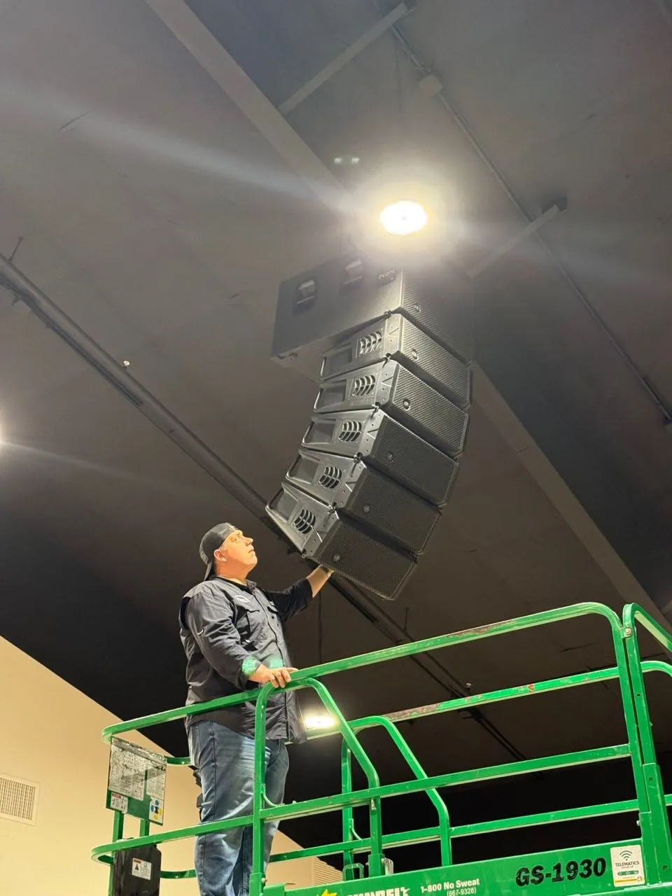 Phase 3 Live technician steadying a curved line array hang during an installation