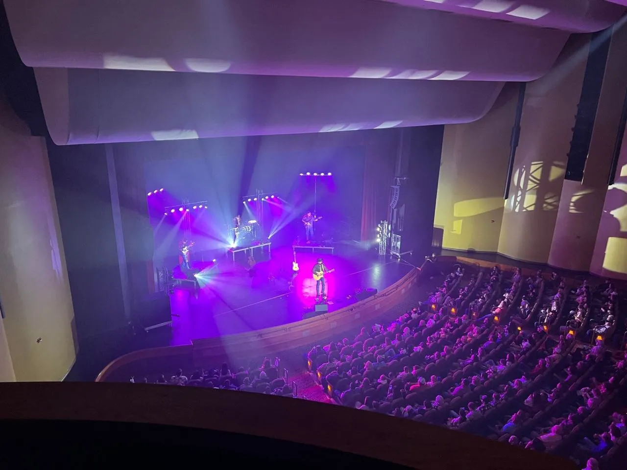 Full theater audience watching a concert with stage lighting designed by Phase 3 Live