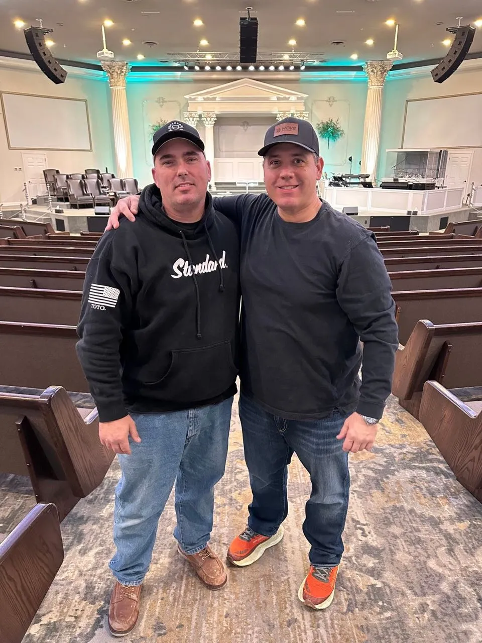 Two crew members posing in a church sanctuary following a Phase 3 Live production setup