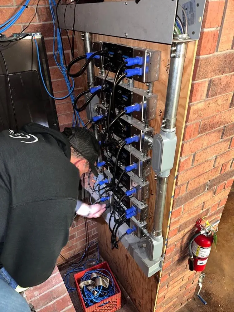 Phase 3 Live technician wiring a power and audio patch panel during a venue installation