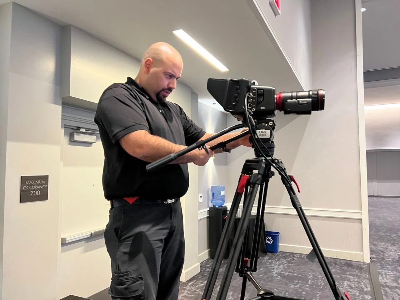 Phase 3 Live videographer setting up a cinema camera on a tripod at a corporate event venue