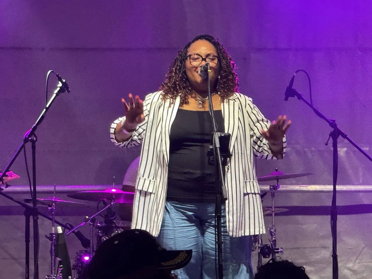 Vocalist performing under purple stage lighting at an outdoor concert produced by Phase 3 Live