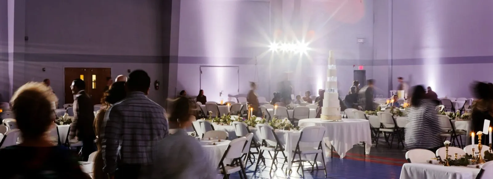 Wedding reception with uplighting and a tiered cake, event lighting by Phase 3 Live