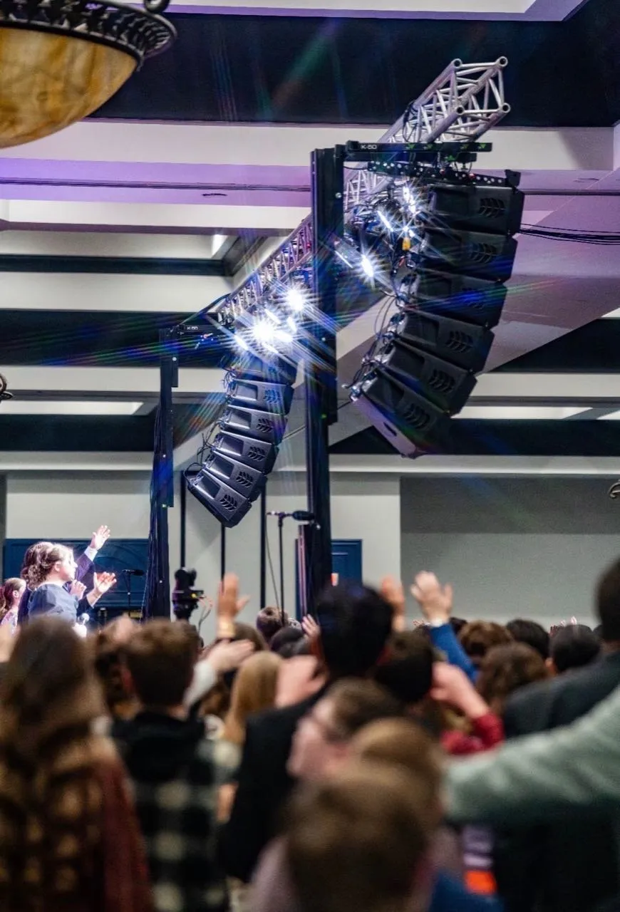 Line-array sound and lighting rig flown by Phase 3 Live above a worship gathering with raised hands